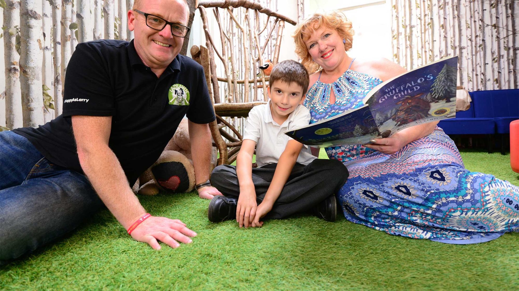 Image of a teacher and student reading a book on artificial grass