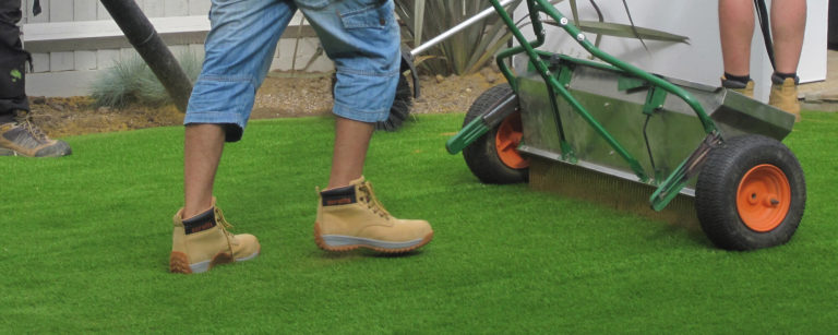 Someone infilling sand on their artificial grass