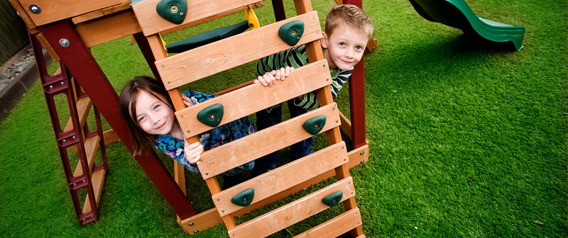 Children playing on a climbing frame on artificial grass