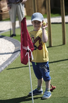 A child playing mini golf on LazyLawn artificial grass