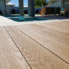 LazyLawn's millboard decking in golden oak by a swimming pool