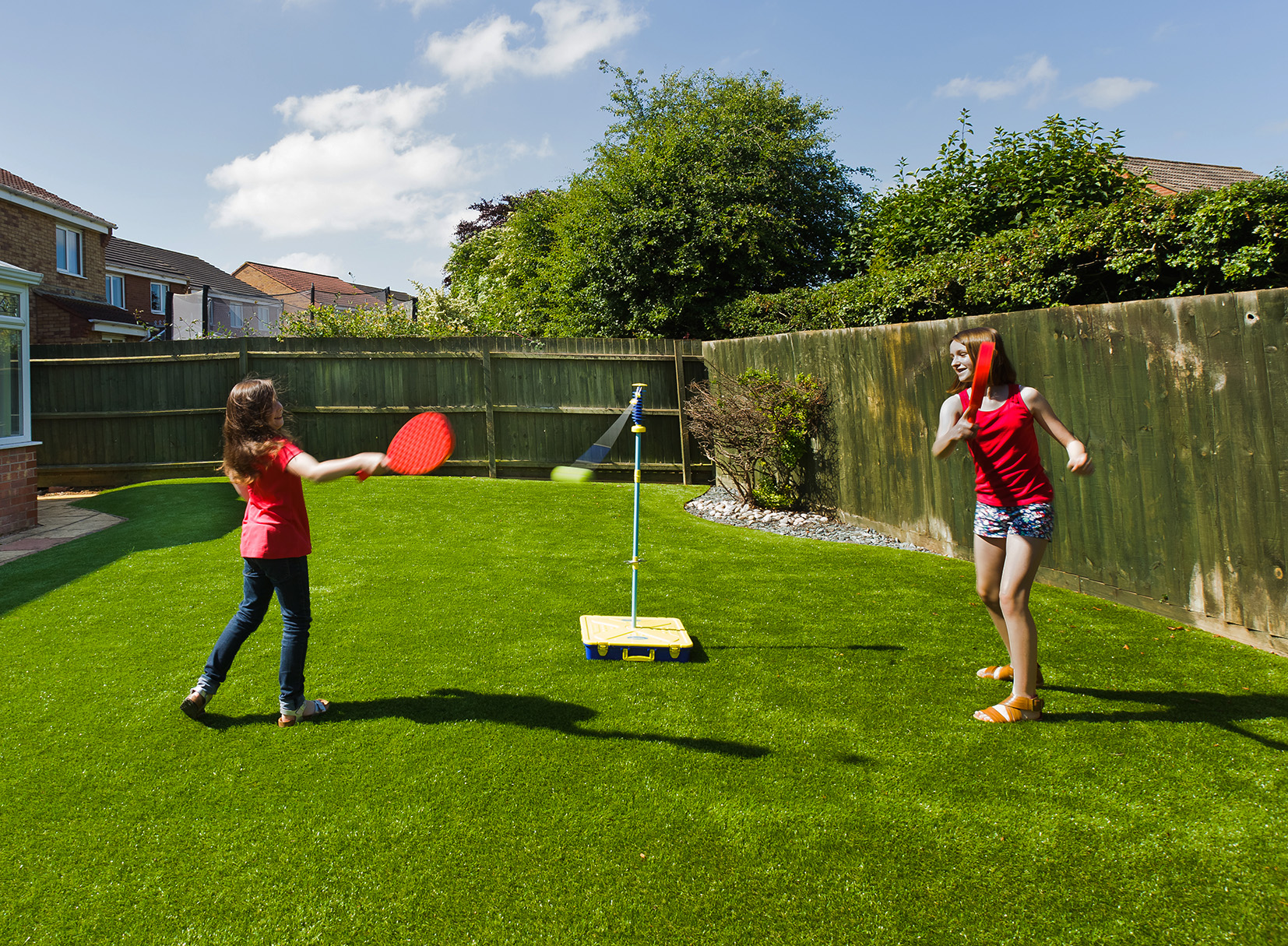 Two Girls Play Swing Ball on Artificial Grass Lawn