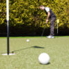 Someone putting a golf ball on artificial grass