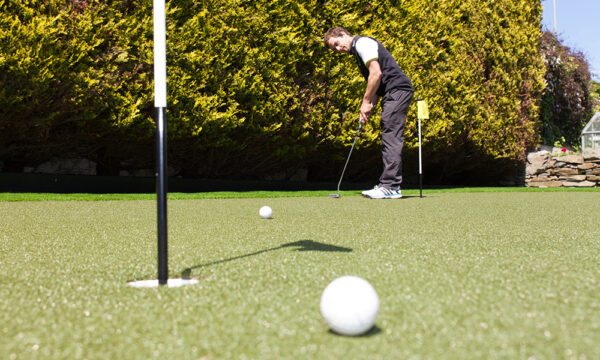 Someone putting a golf ball on artificial grass